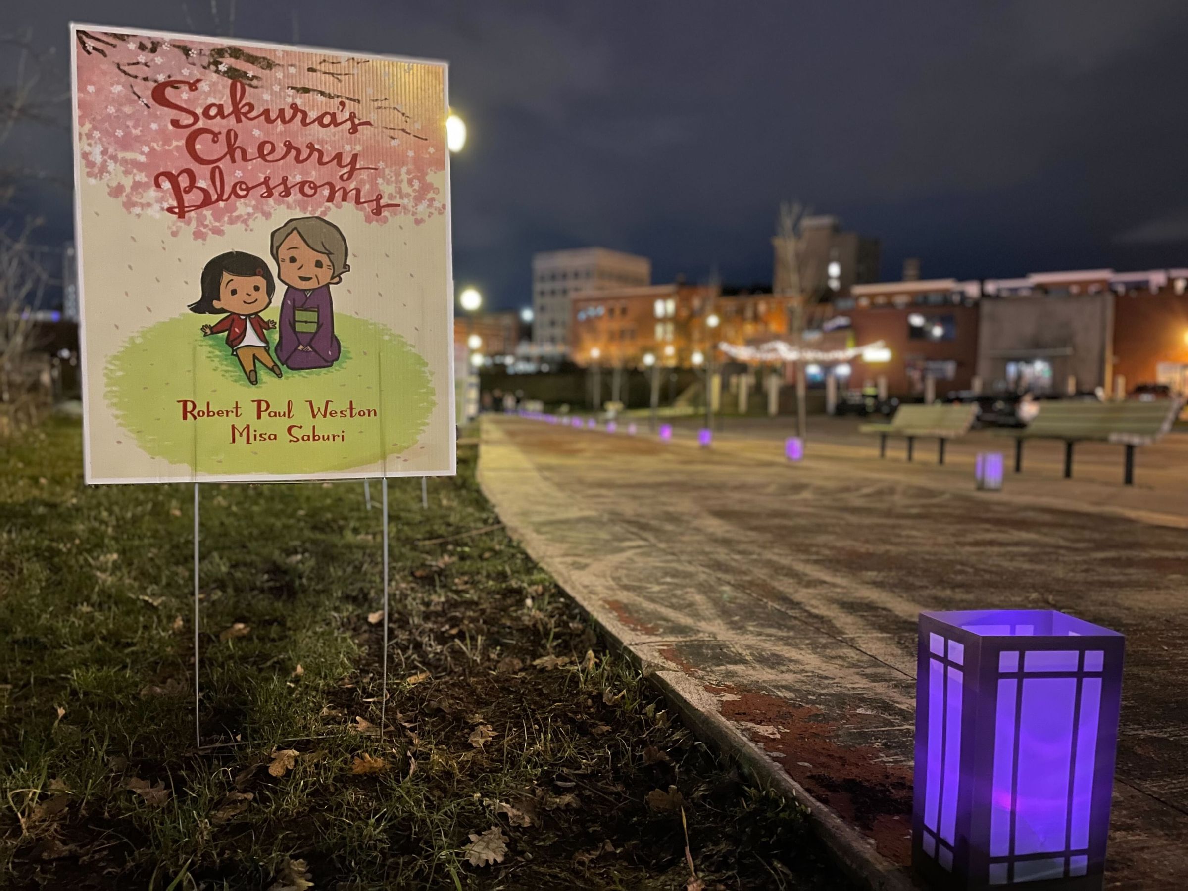 A sign printed with the pink, red, and green book cover of 